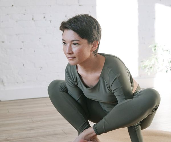 Woman in a calm yoga pose in a bright, serene room.